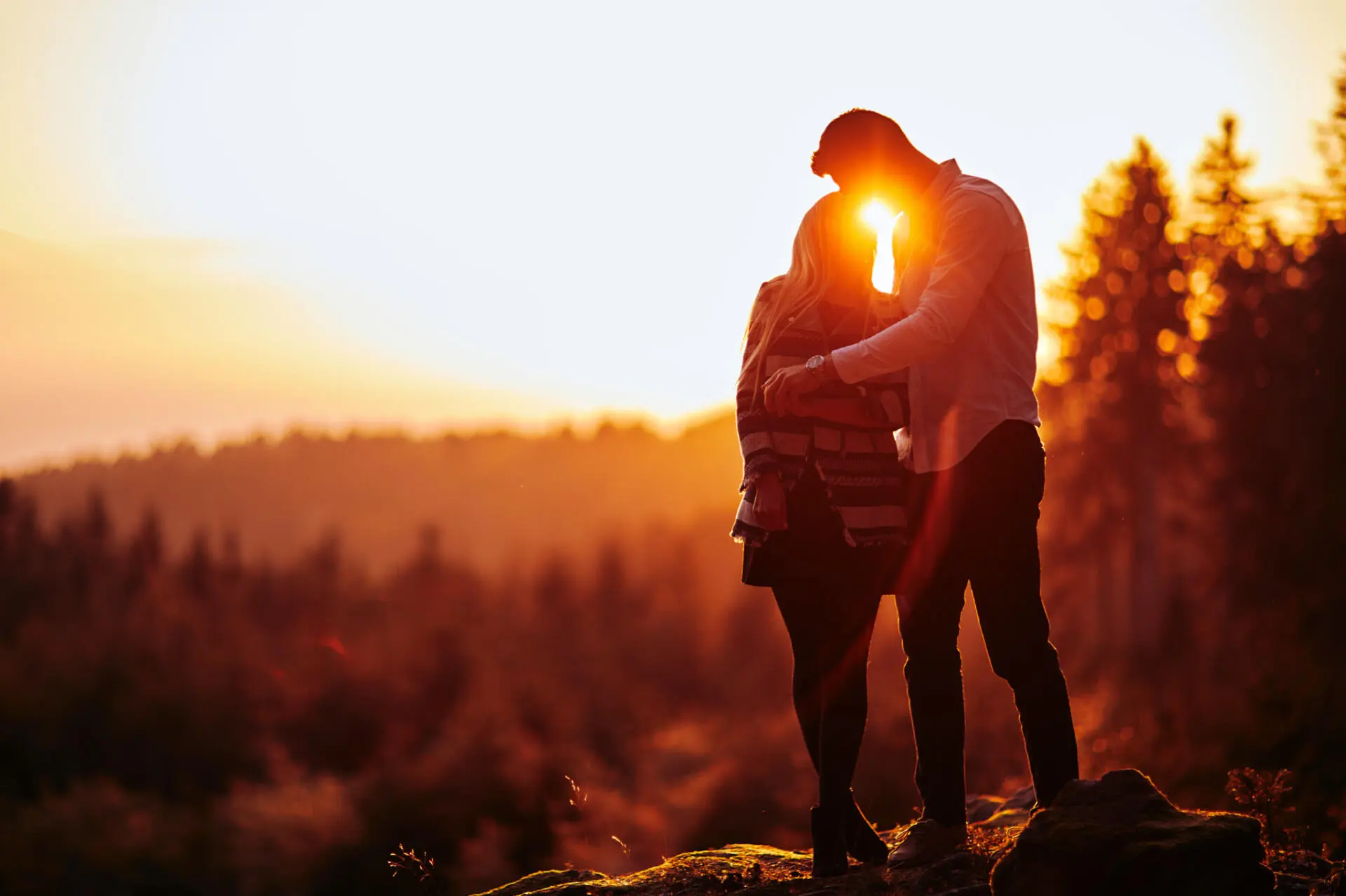 Paar umarmt sich auf den Felsen im goldenen Abendlicht